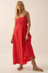 woman wearing a red maxi dress with cut-out details and a flowing silhouette, standing against a neutral background