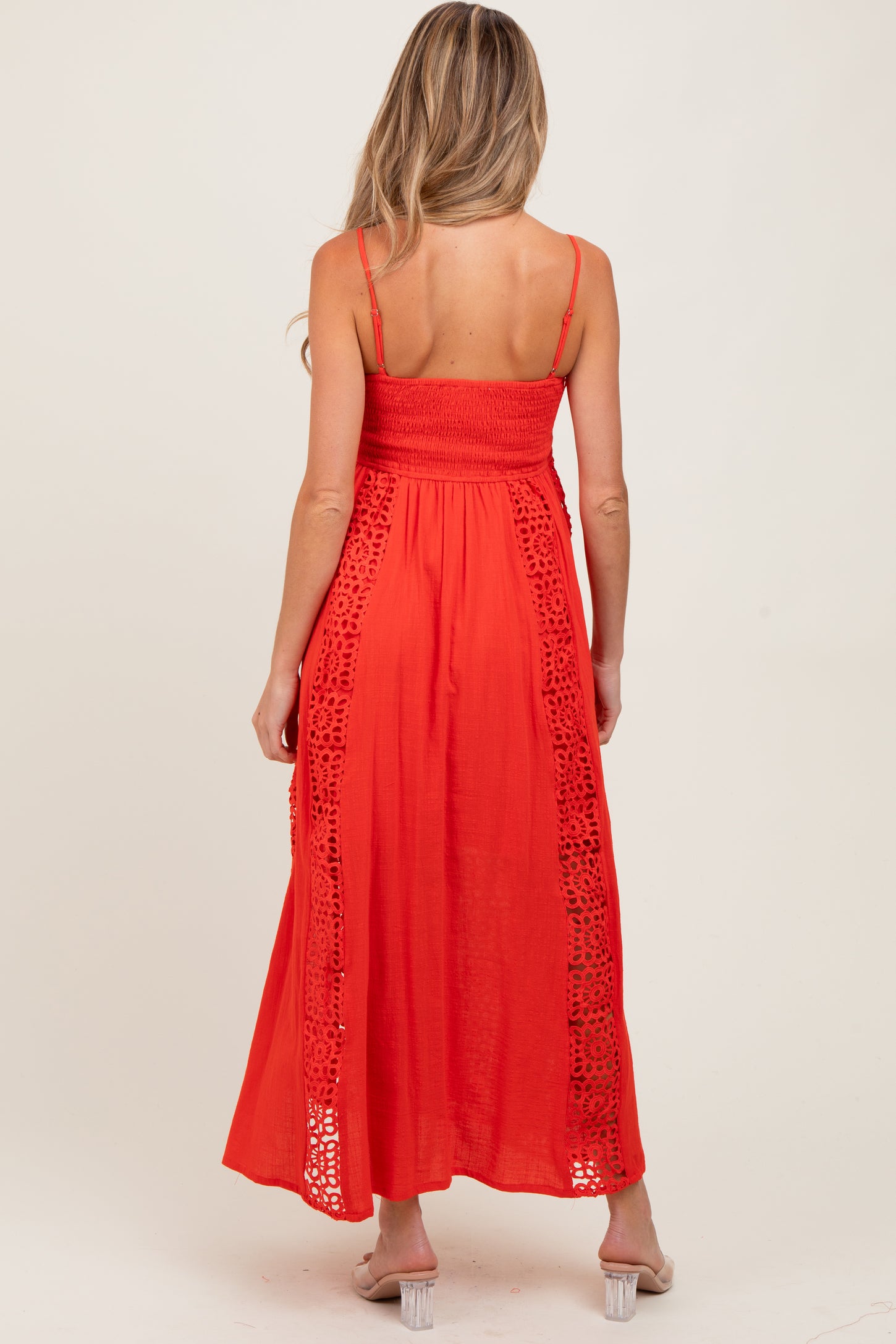 woman wearing a red maternity maxi dress with smocked bodice and lace details on the sides