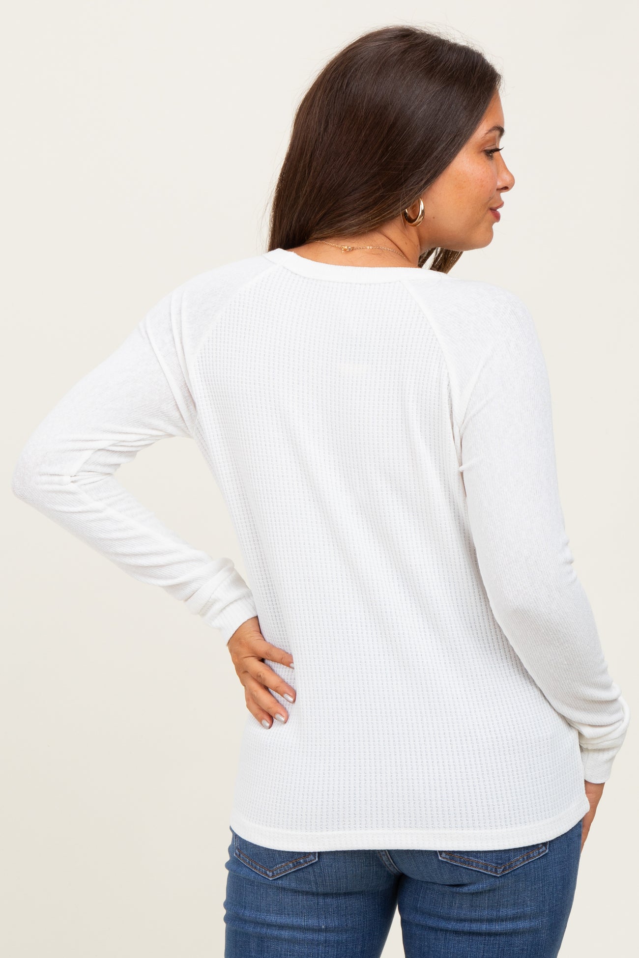woman wearing a white ribbed maternity top, showing the back view with long sleeves and a relaxed fit