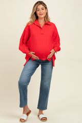 woman wearing a red maternity pullover with a collar and a baby bump, paired with blue jeans and sandals