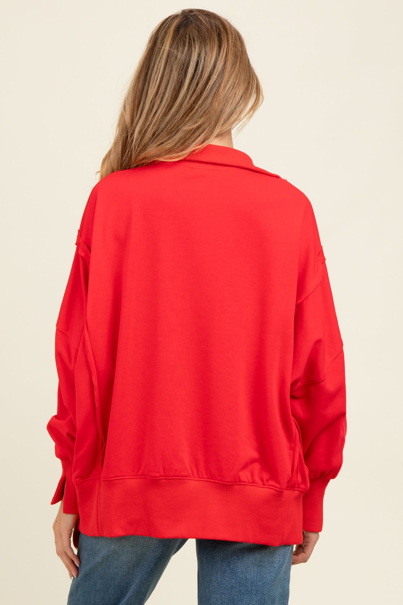 woman wearing a bright red oversized maternity sweatshirt from the back