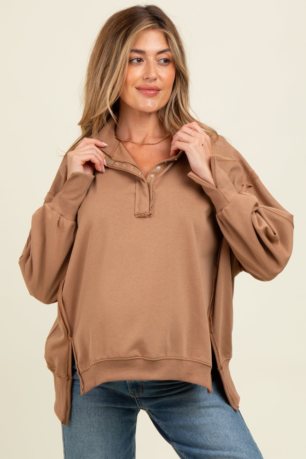 woman wearing a tan maternity pullover sweatshirt with a quarter-zip and long sleeves, styled with casual jeans