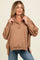 woman wearing a tan maternity pullover sweatshirt with a quarter-zip and long sleeves, styled with casual jeans