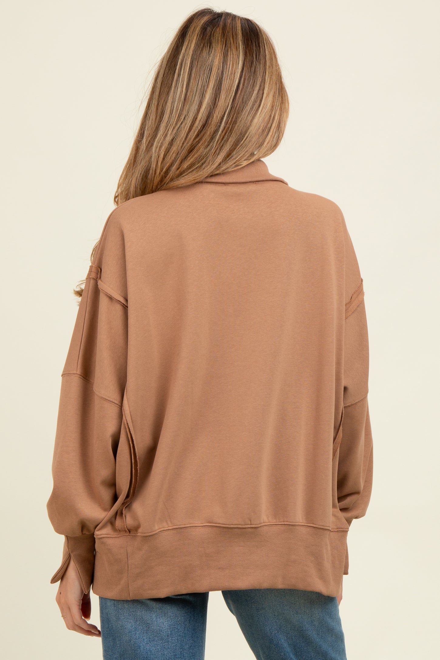woman wearing a brown oversized maternity sweatshirt, styled with a relaxed fit and elevated neckline, seen from the back