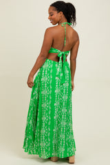 woman wearing a green backless maxi dress with a halter tie and floral patterns