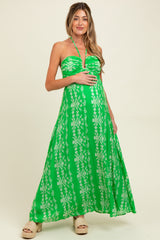 woman wearing a green strapless maxi dress with floral patterns and holding her baby bump