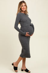 woman wearing a charcoal gray ribbed maternity dress with a belt and holding her baby bump