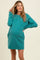woman wearing a teal maternity sweatshirt dress with side pockets and a visible baby bump