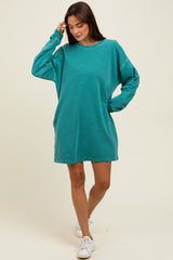 woman wearing a teal oversized sweatshirt dress styled with white sneakers