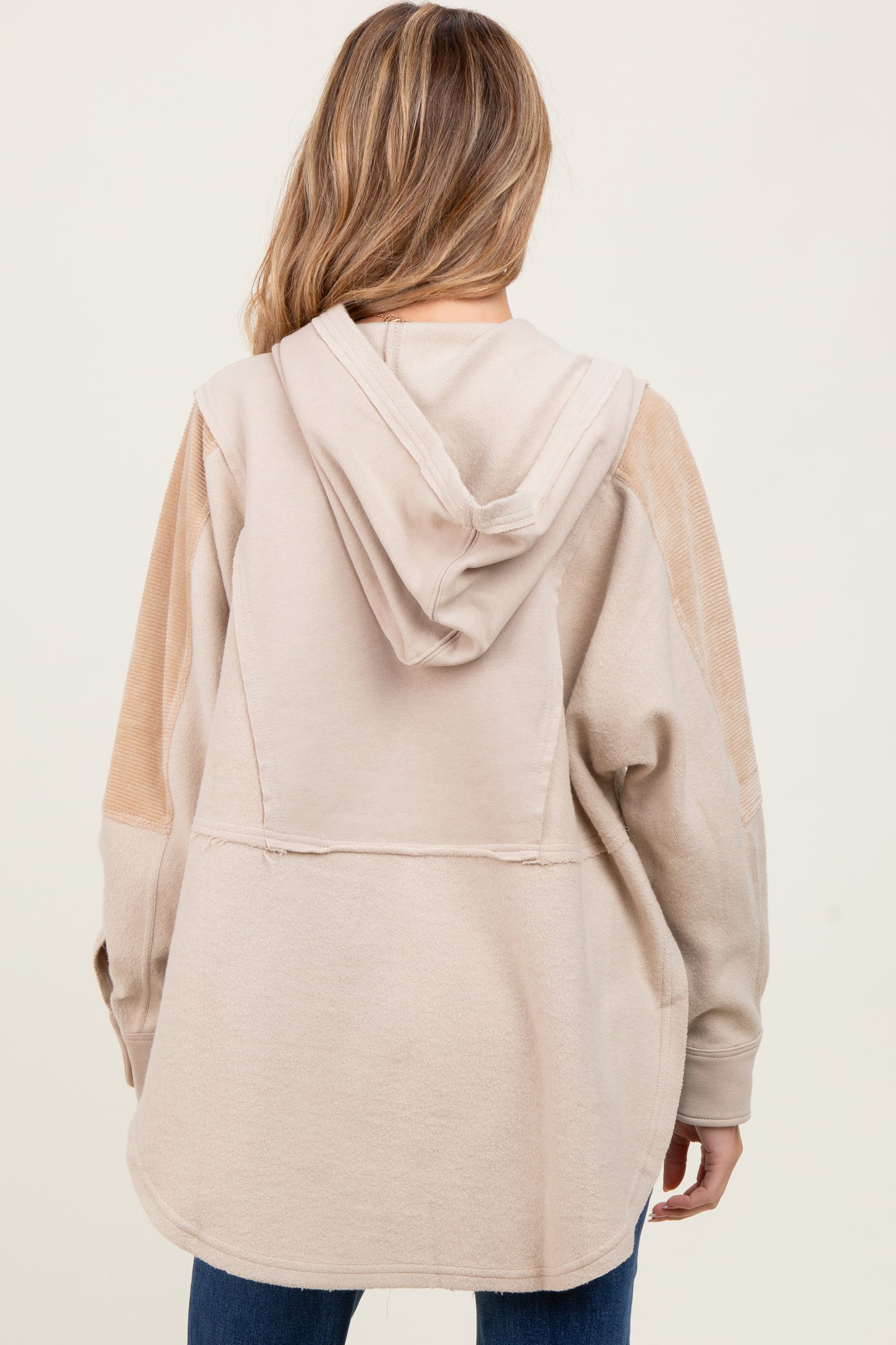 woman wearing a beige maternity hoodie with a relaxed fit and a hood, showing the back view