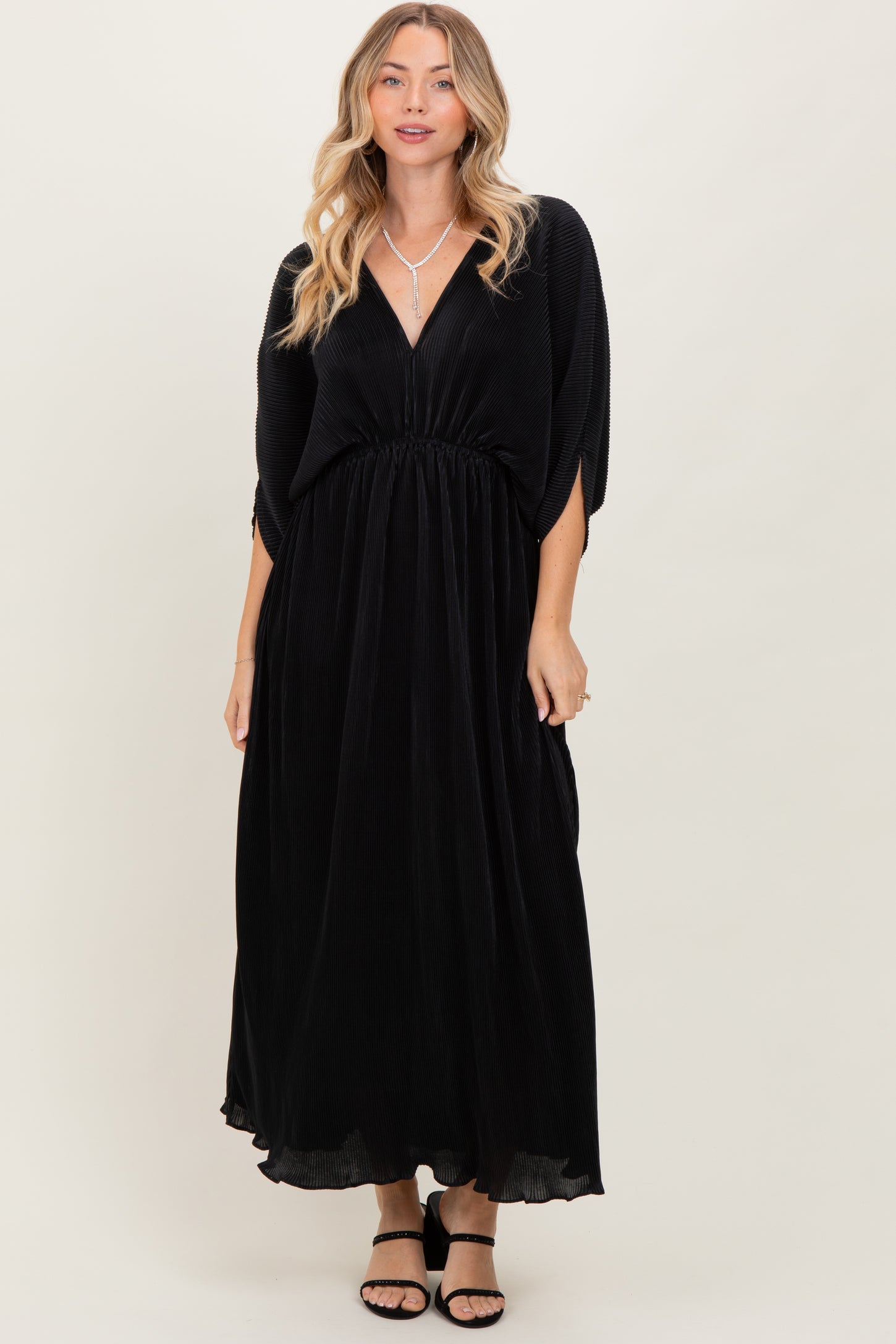 woman wearing a black maxi dress with a deep v-neck and elastic waist, styled with open-toe sandals
