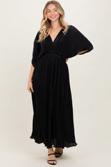 woman wearing a black maxi dress with a deep v-neck and cinched waist, smiling and posing against a light background