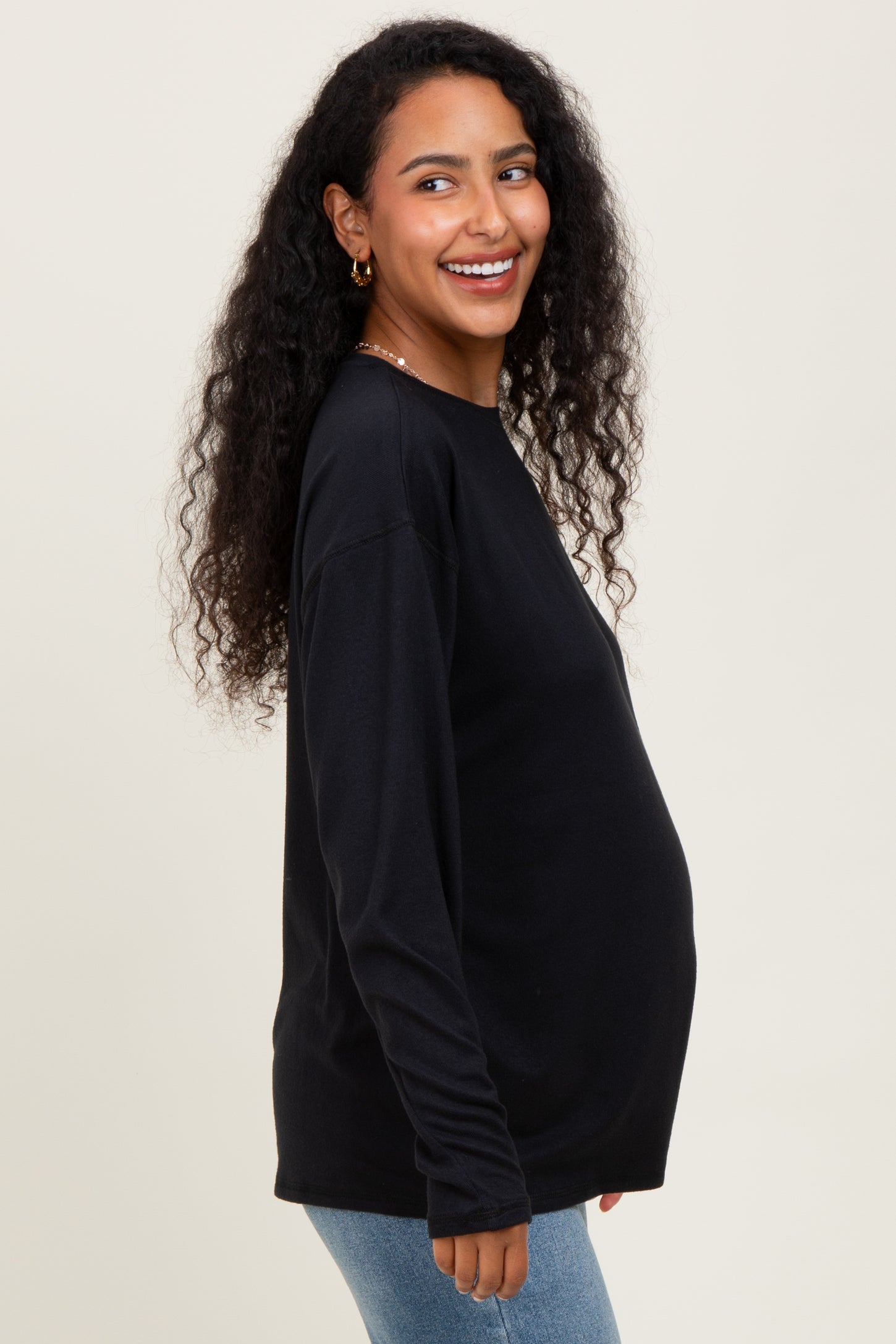 woman wearing a black long sleeve maternity top and showing her baby bump