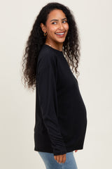 woman wearing a black long sleeve maternity top and showing her baby bump