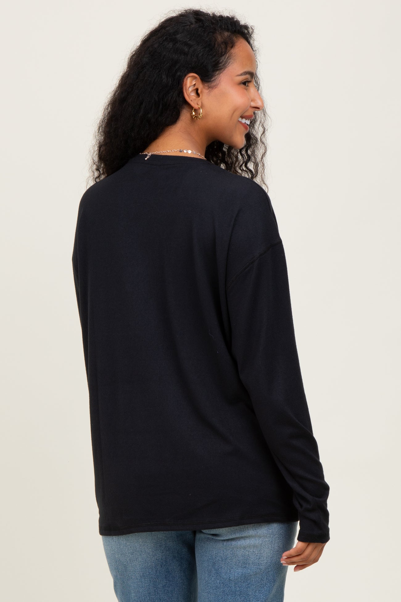 woman wearing a black long sleeve maternity top, showing the back view with relaxed fit and round neckline