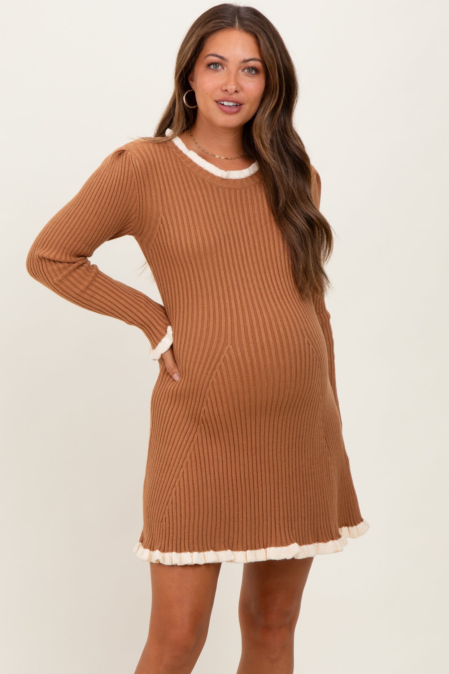 woman wearing a rust ribbed maternity dress with cream ruffle trim and a visible baby bump