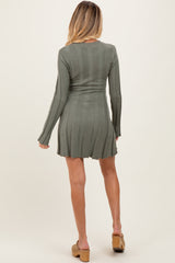 woman wearing a long sleeve olive green ribbed maternity dress with a fitted waist and flared skirt