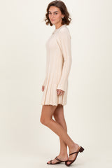 woman wearing a beige ribbed long sleeve dress with a flared hem and styled with open-toe heeled sandals