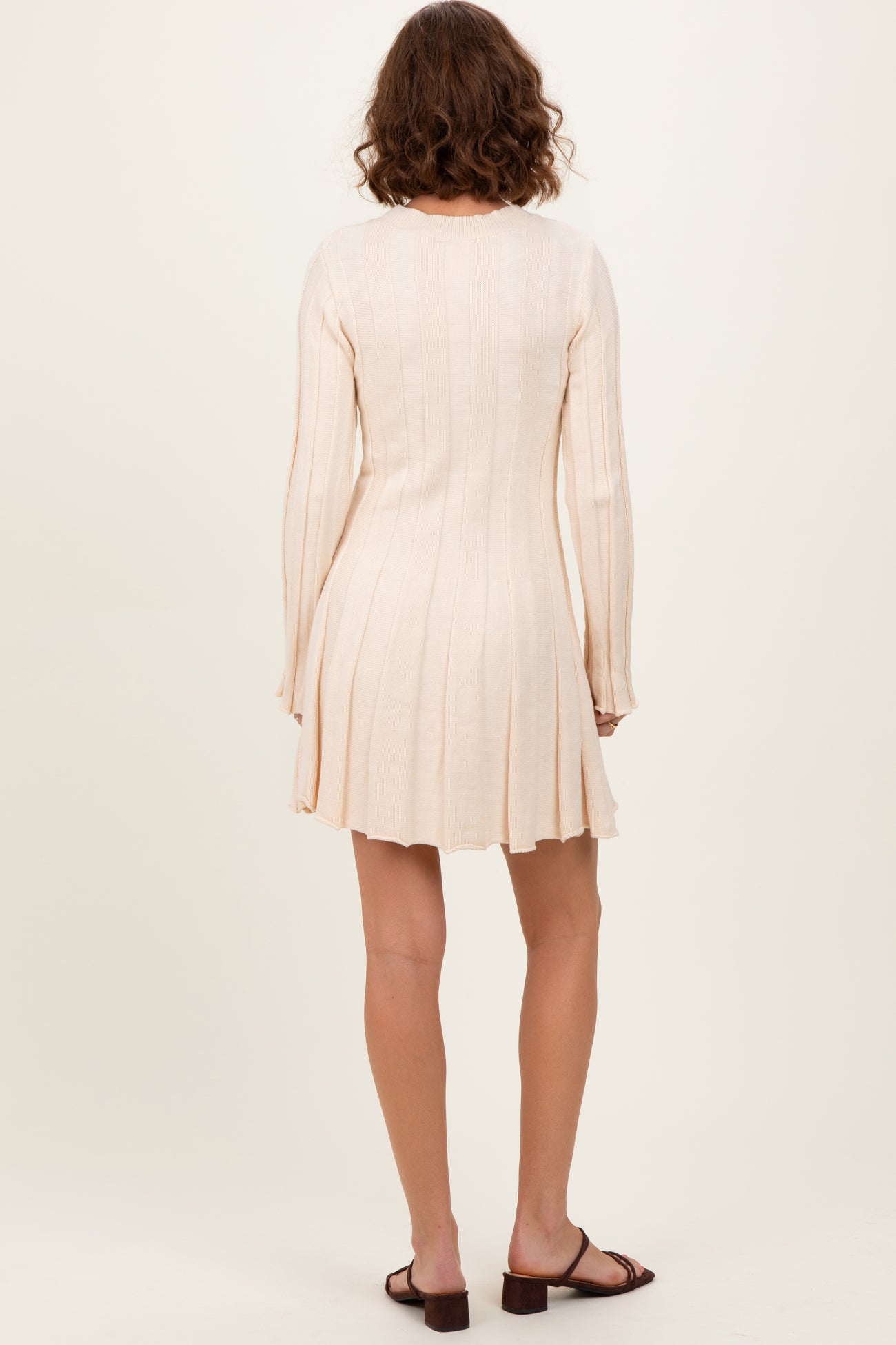 woman wearing a ribbed light beige long sleeve mini dress with a flared skirt and back view shown