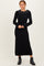 woman wearing a black long sleeve sweater dress with a decorative pearl collar and ankle boots