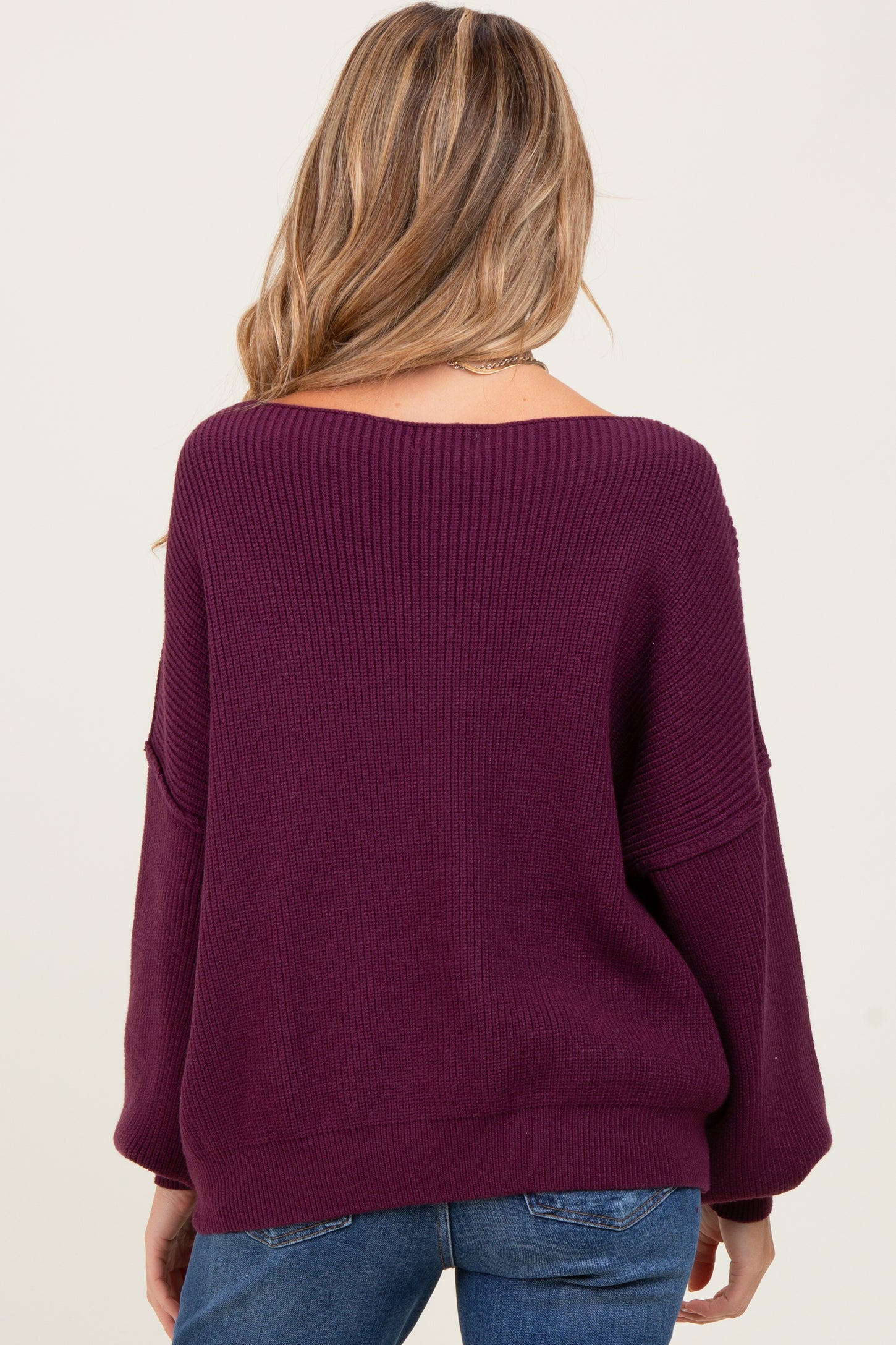 woman wearing a purple oversized off-the-shoulder maternity sweater, shown from the back with loose sleeves