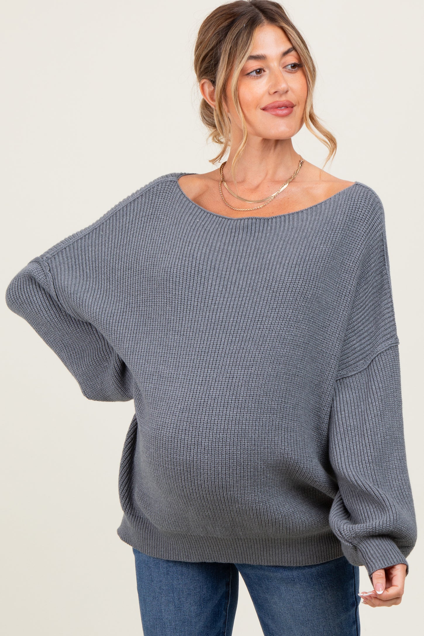 woman wearing a gray oversized ribbed maternity sweater and showing her baby bump