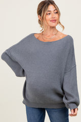 woman wearing a gray oversized ribbed maternity sweater and showing her baby bump