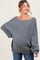 woman wearing a gray oversized ribbed maternity sweater and showing her baby bump