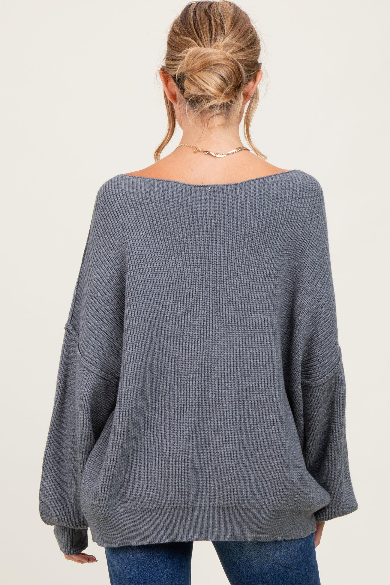 woman wearing a gray oversized ribbed maternity sweater, showing the back view with relaxed fit and long sleeves