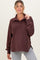 woman wearing a burgundy maternity pullover with a collar and button details, paired with gray leggings