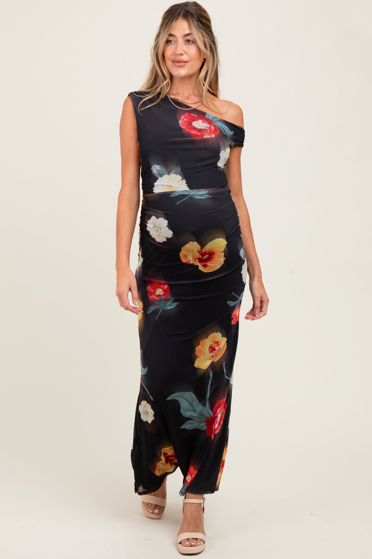woman wearing a black floral off-shoulder maternity dress with ruching, showcasing her baby bump