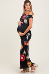 woman wearing a black floral off-shoulder maternity dress and showing her baby bump