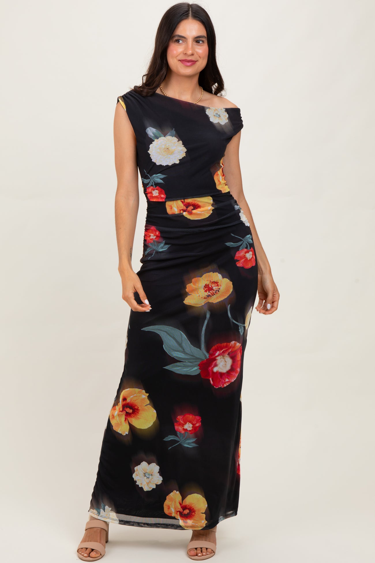 woman wearing a black off-shoulder floral maxi dress with colorful flowers and a fitted silhouette