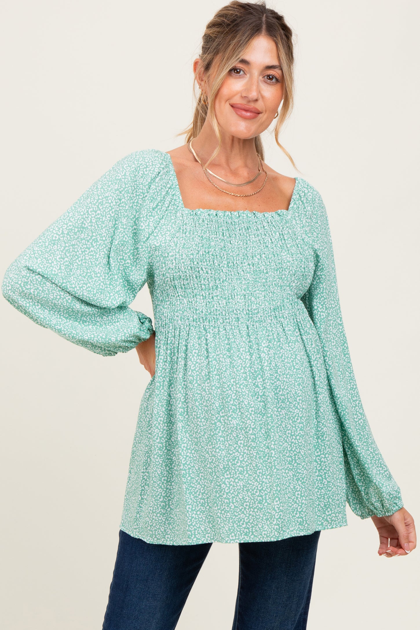 woman wearing a mint green maternity top with square neckline and smocked bodice, showcasing her baby bump