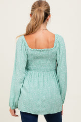 woman wearing a mint green maternity top with a smocked back and long sleeves, view from the back