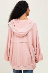woman wearing a light pink oversized maternity hoodie with a hood and drop sleeves, viewed from the back