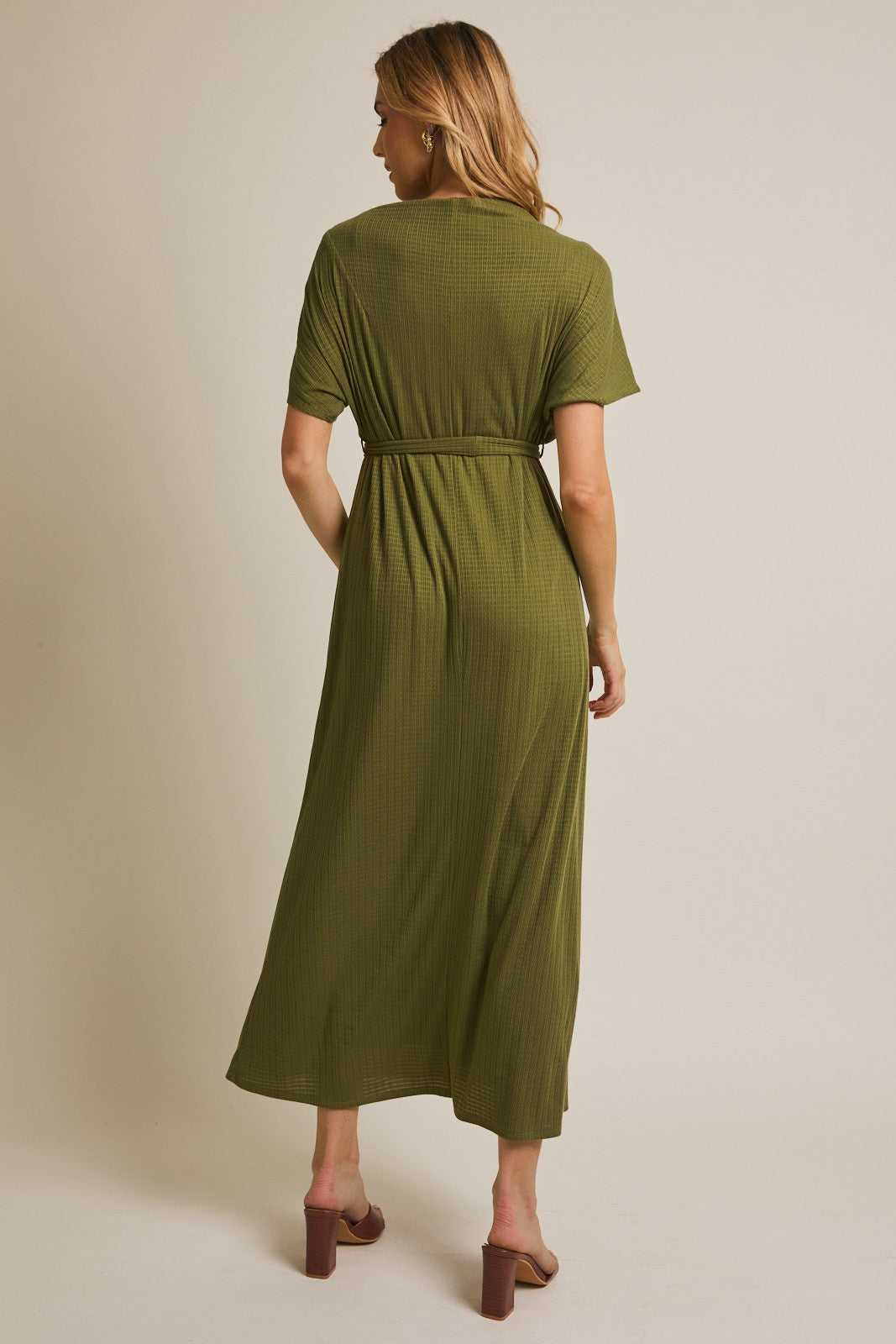 woman wearing an olive green short sleeve maxi dress with a belted waist, shown from the back