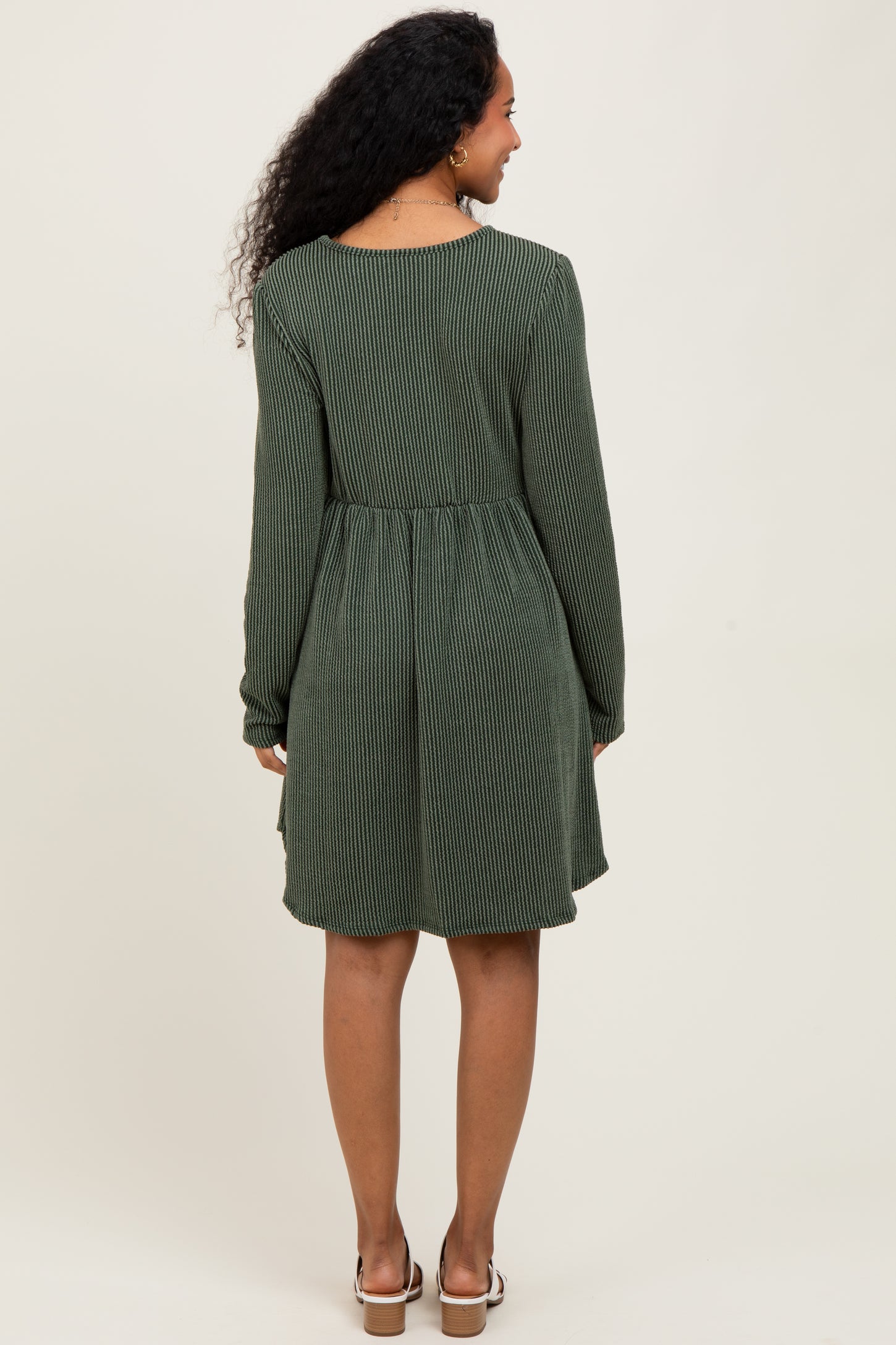 woman wearing a green striped maternity dress with long sleeves and a relaxed fit, showing the back view