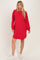 woman wearing a red ribbed long sleeve sweater dress with side slits and white sneakers