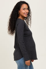 woman wearing a dark gray long sleeve maternity top and showing her baby bump