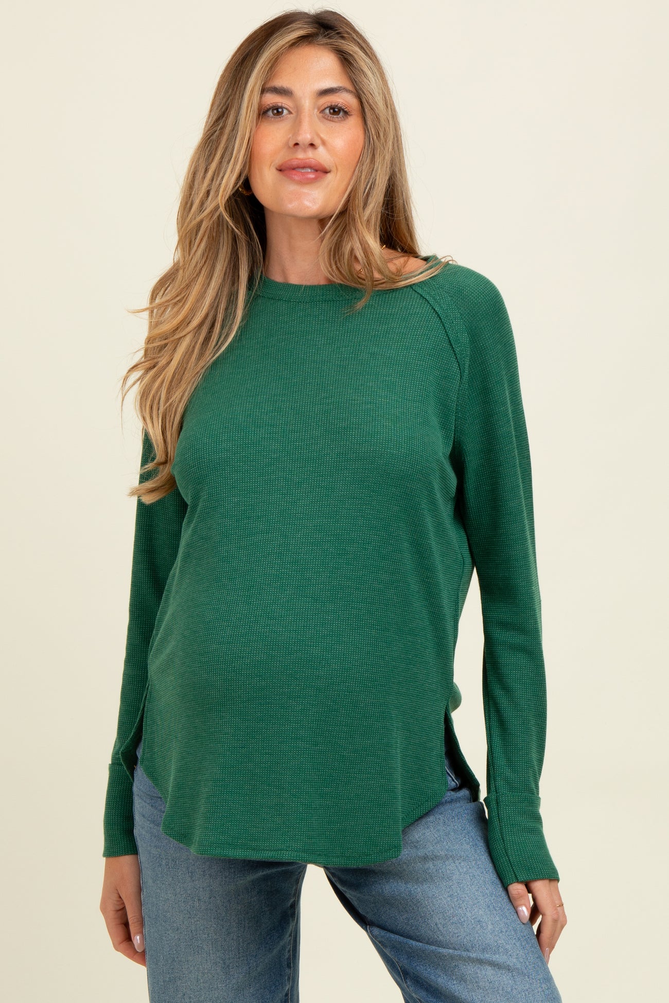 woman wearing a green long sleeve maternity top with a relaxed fit and side slits, showing her baby bump