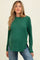 woman wearing a green long sleeve maternity top with a relaxed fit and side slits, showing her baby bump