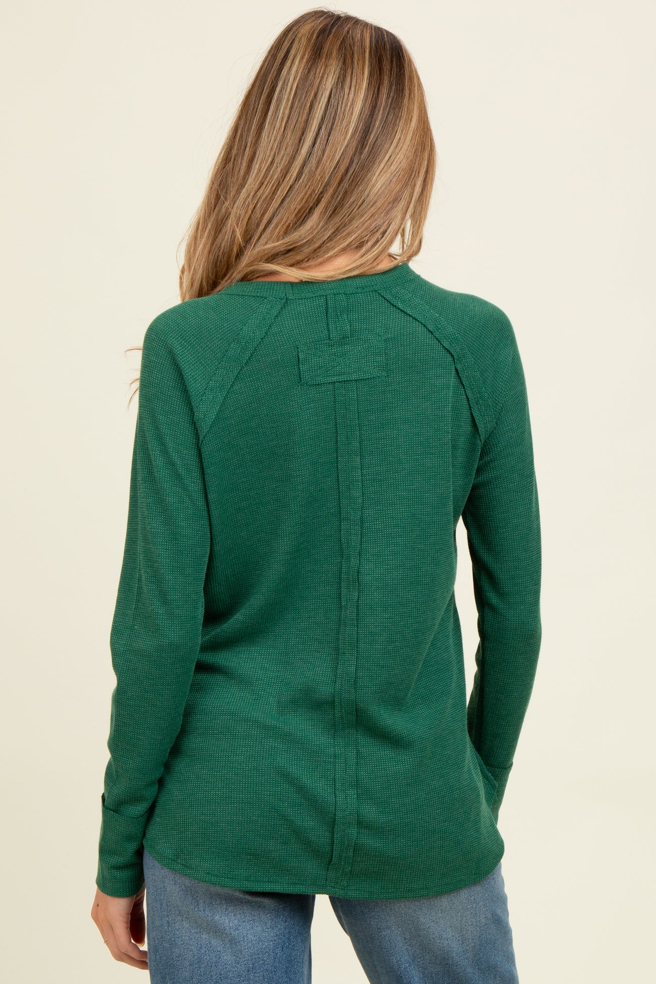 woman wearing a green long sleeve maternity top with a back seam detail and relaxed fit