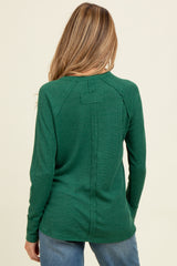 woman wearing a green long sleeve maternity top with a back seam detail and relaxed fit