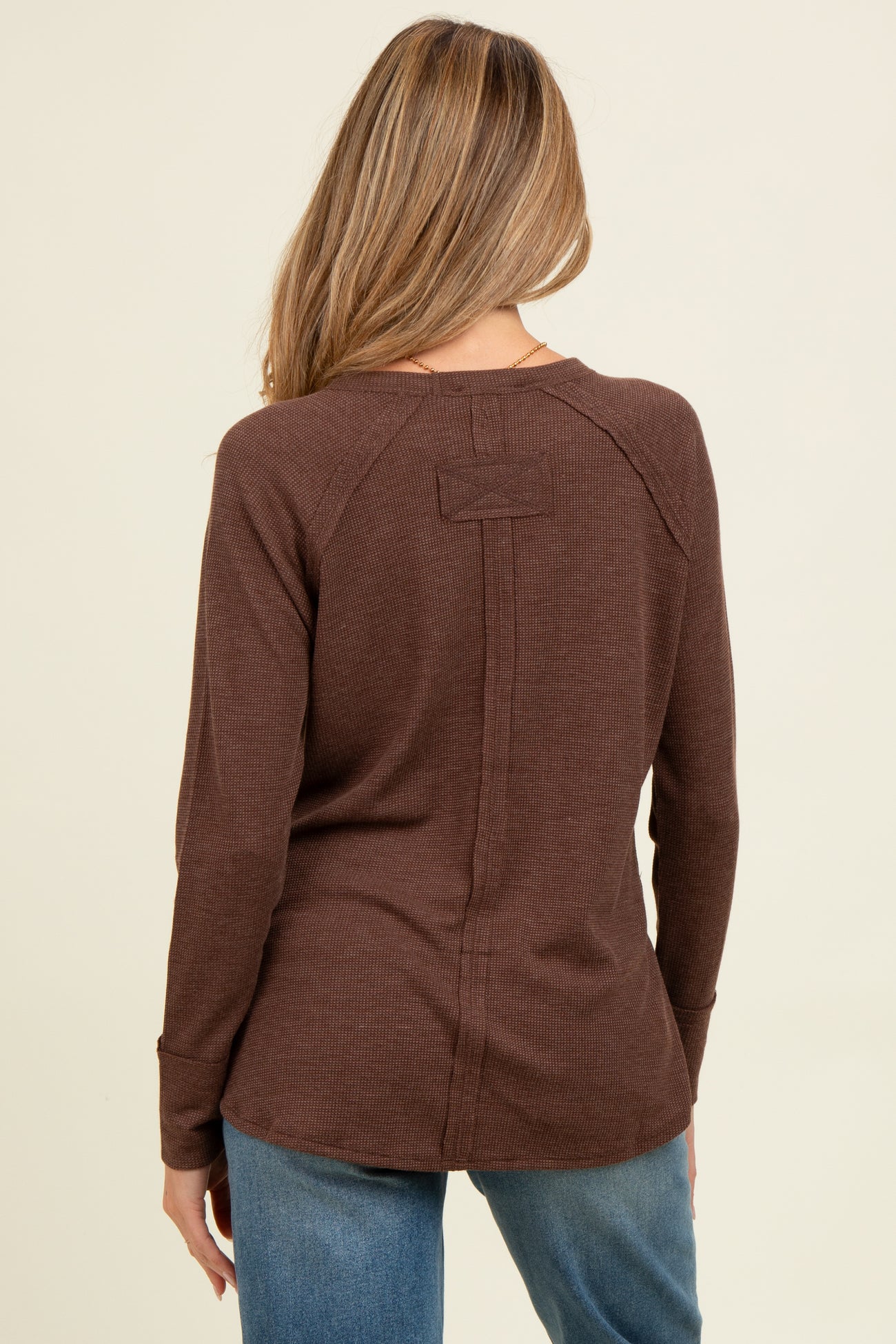 woman wearing a brown long sleeve maternity top, showing the back view with a relaxed fit and seam detailing