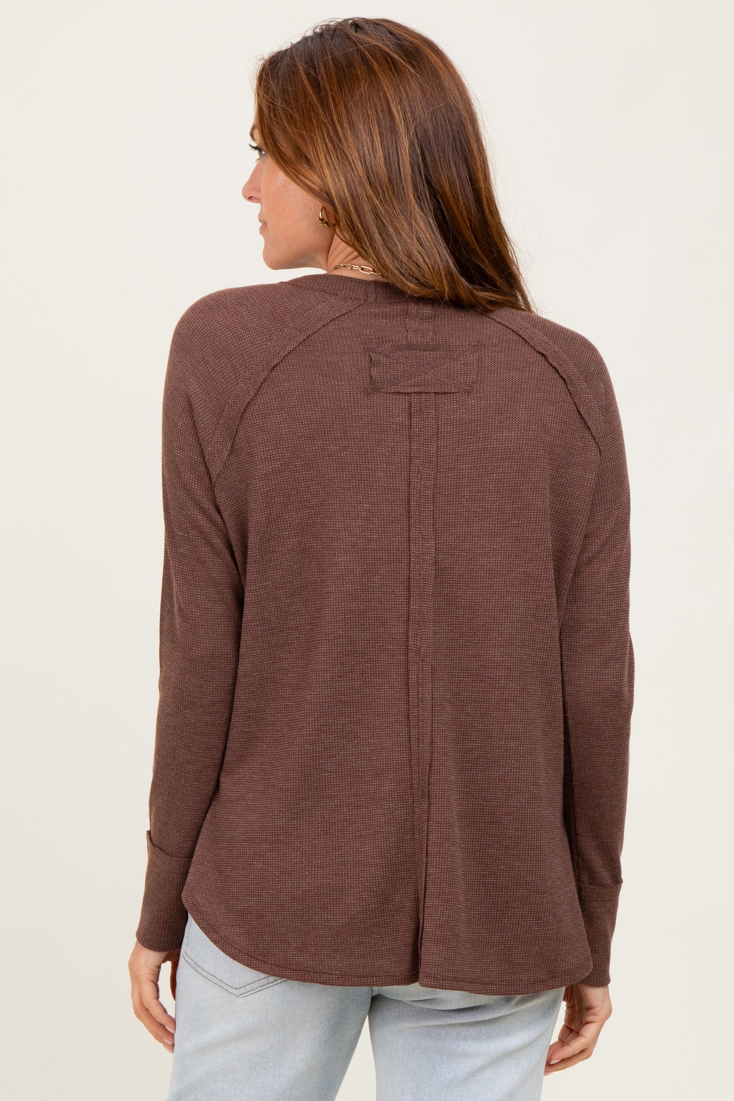 woman wearing a brown long sleeve top with a relaxed fit and a back seam detail
