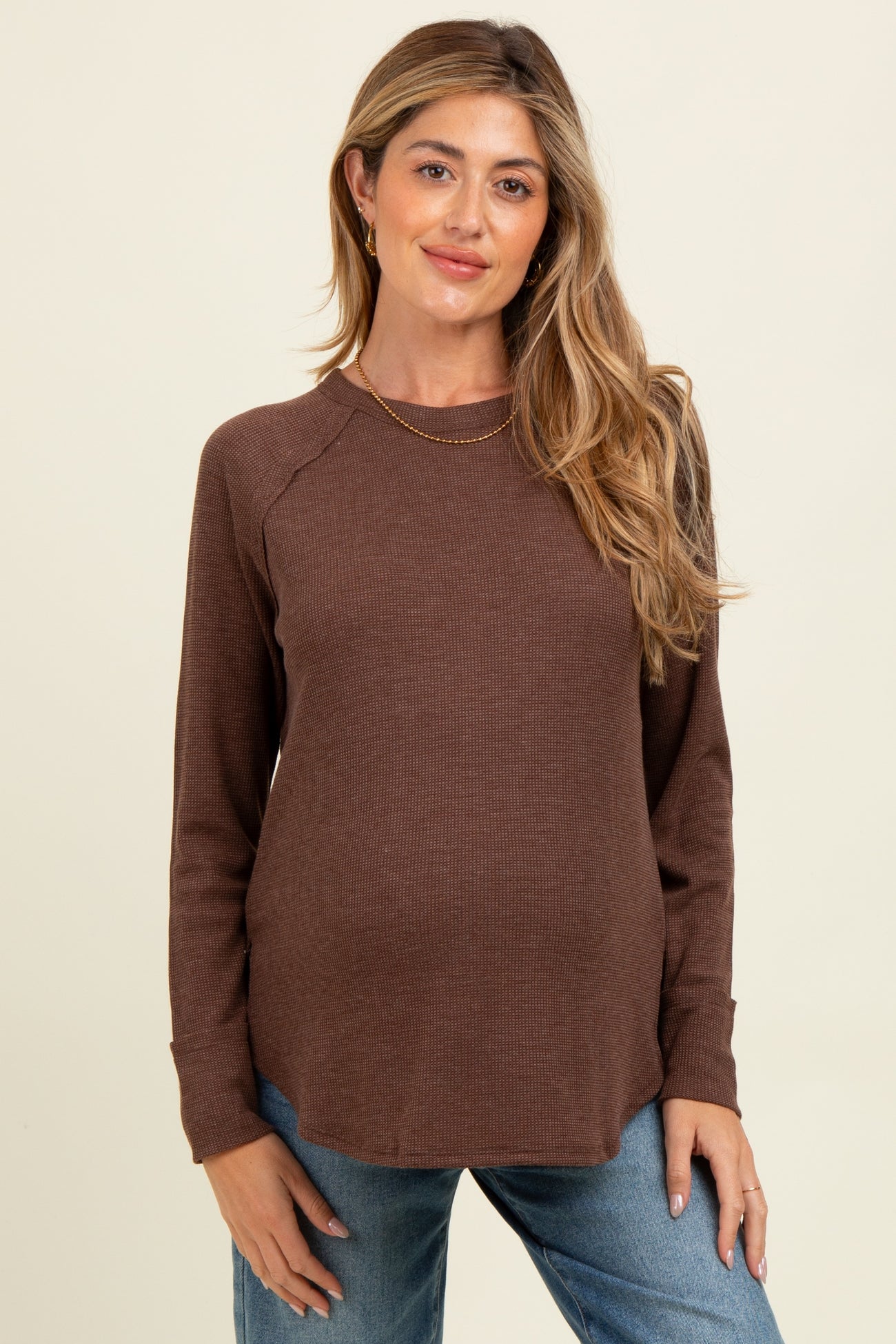 woman wearing a brown long sleeve maternity top with a relaxed fit and a baby bump visible