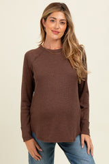 woman wearing a brown long sleeve maternity top with a relaxed fit and a baby bump visible