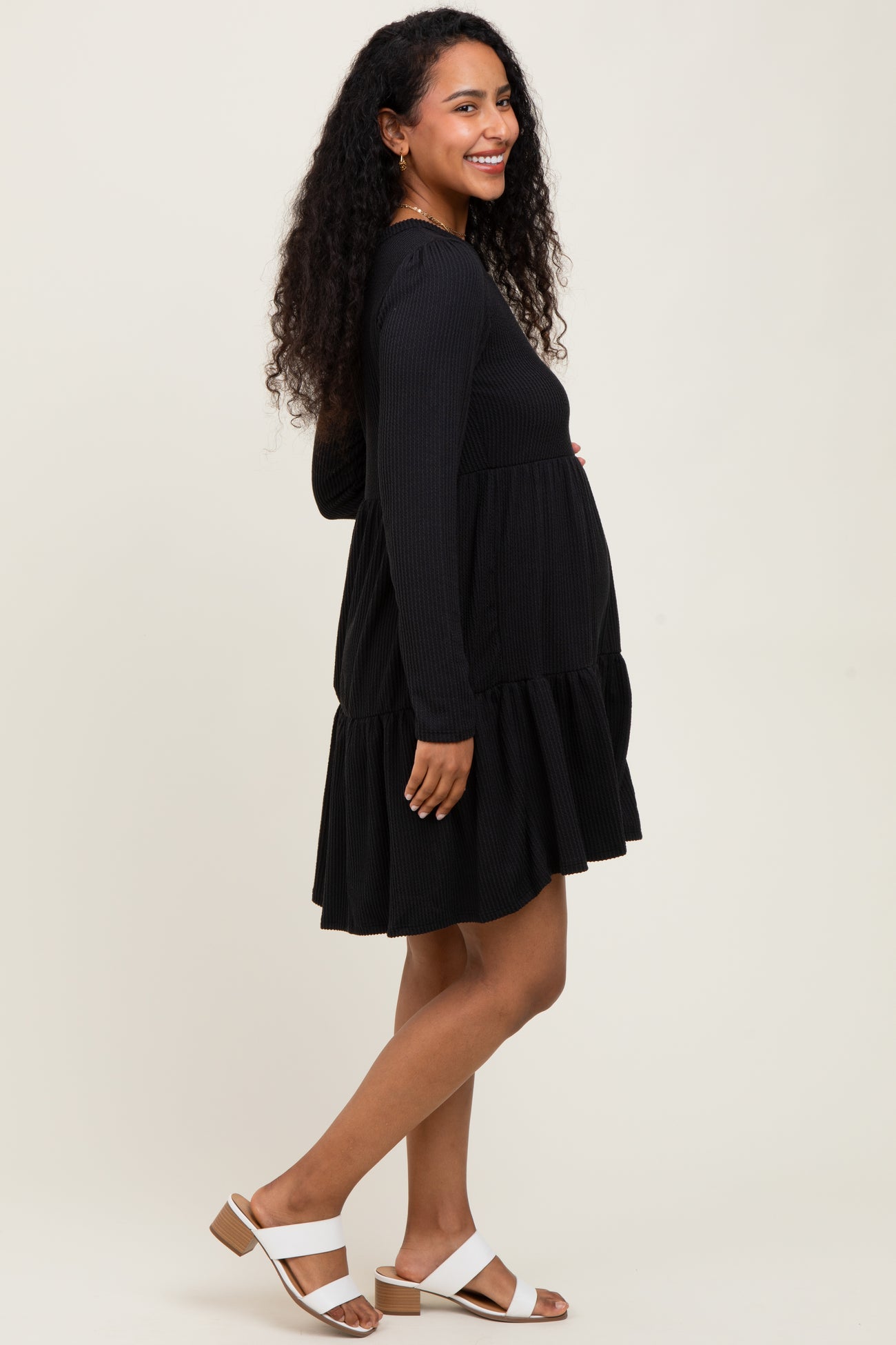 woman wearing a black ribbed long sleeve maternity dress with a tiered skirt and a visible baby bump