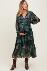 woman wearing a navy floral maternity maxi dress, holding her baby bump, with long sleeves and a tiered skirt